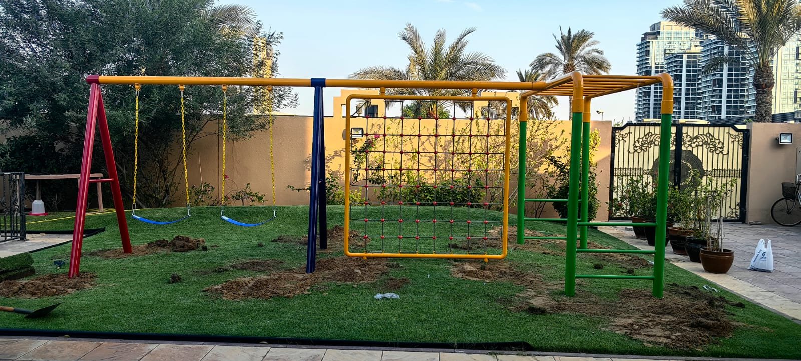 Custom outdoor playground with swings and climbing frames installed in a residential courtyard.